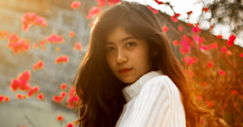 sultry filipino woman near red flowers